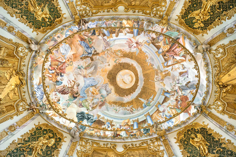Barocke Deckenmalerei mit kunstvollen Fresken, vergoldeten Verzierungen und religiösen Motiven in einer Kirche